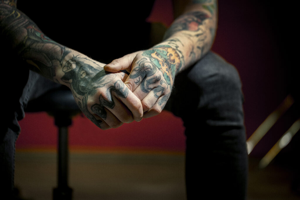 Close-up of Love and Rich tattoos on hands