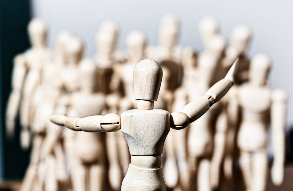 Wooden figurine in front of crowd of other marionettes
