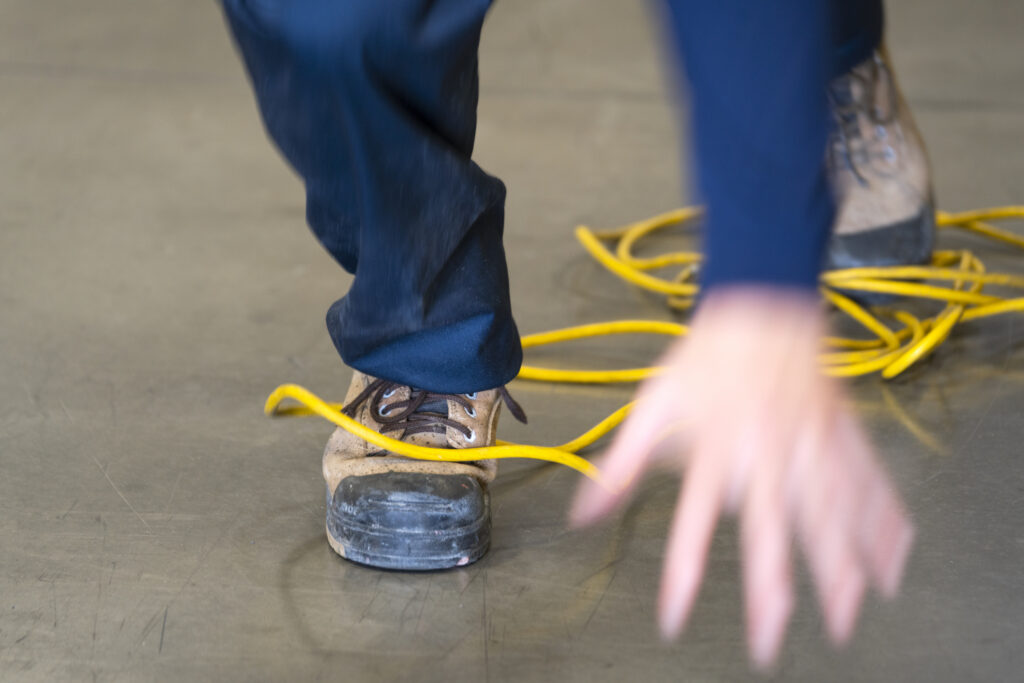 A worker tripping over an electrical cord in an industrial environment
