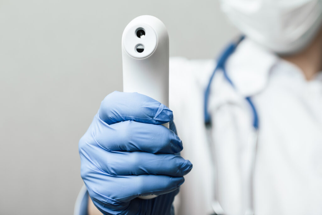 Doctor pointing infrared thermometer gun to check body temperature epidemic virus outbreak concept