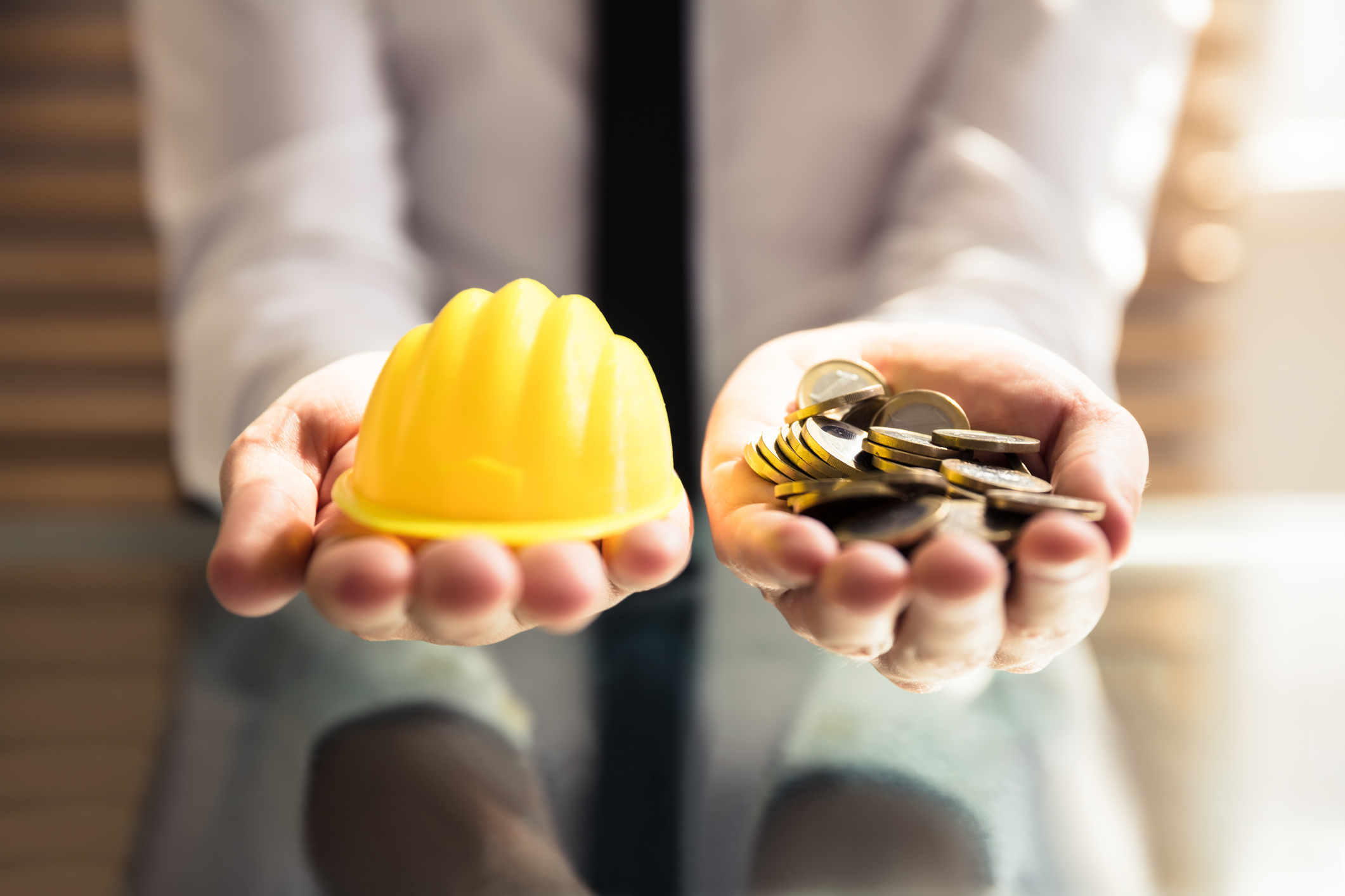 Human Hand Holding Hardhat And Many Golden Coins