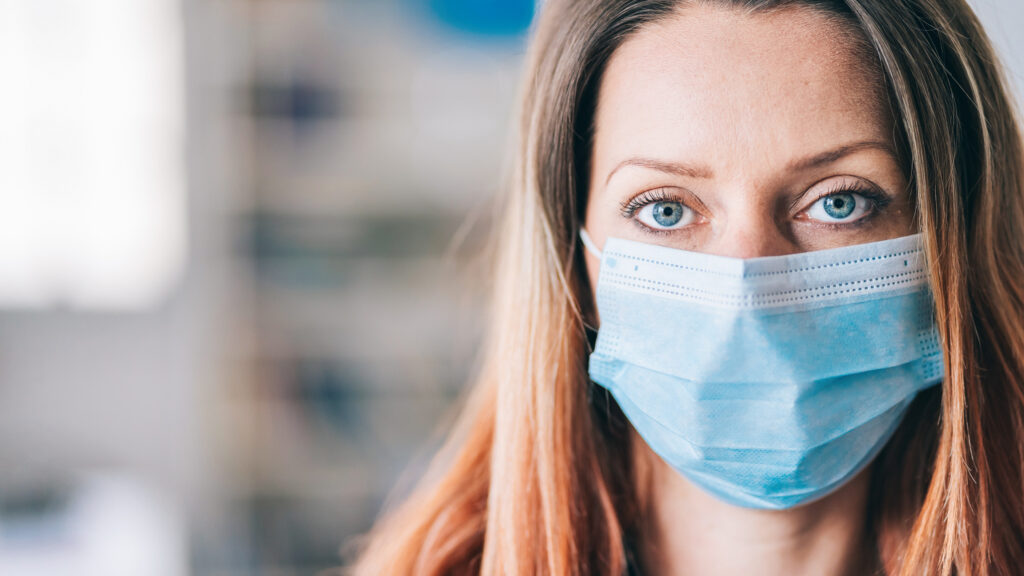 Woman wearing protective face mask in the office for safety and protection during COVID-19