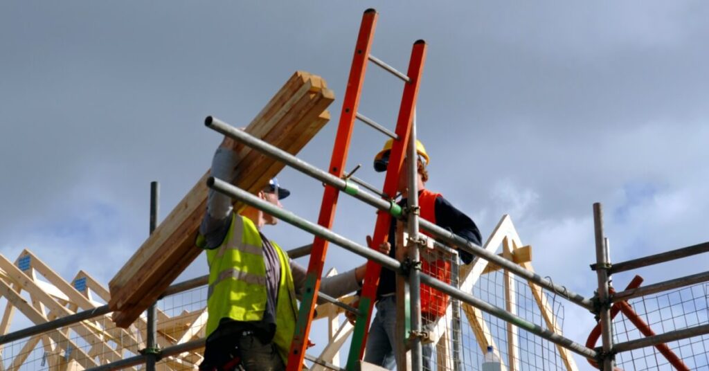 low-view-of-two-construction-workers-on-top-of-house-frame (1)