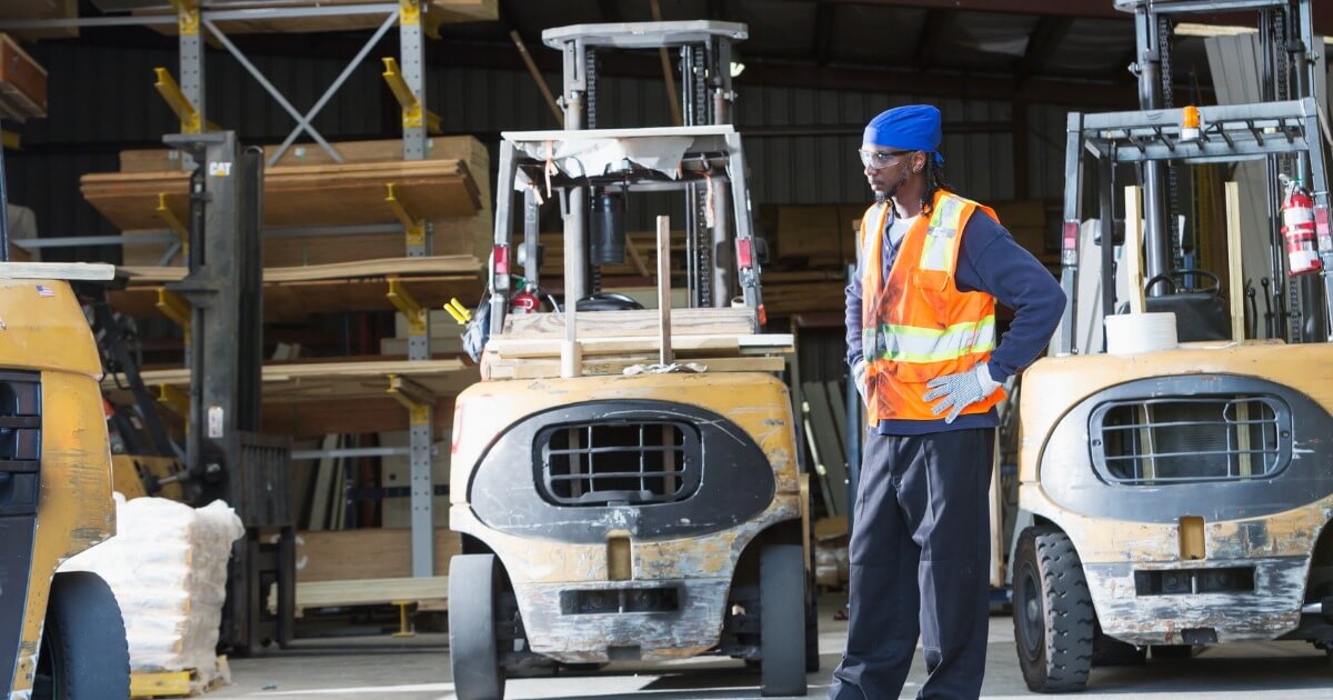 mature-black-man-in-warehouse-standing-by-forklifts