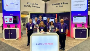 Seven people stand at a trade show booth for Novara, an all-in-one safety software, with screens displaying demos and informational banners in the background.