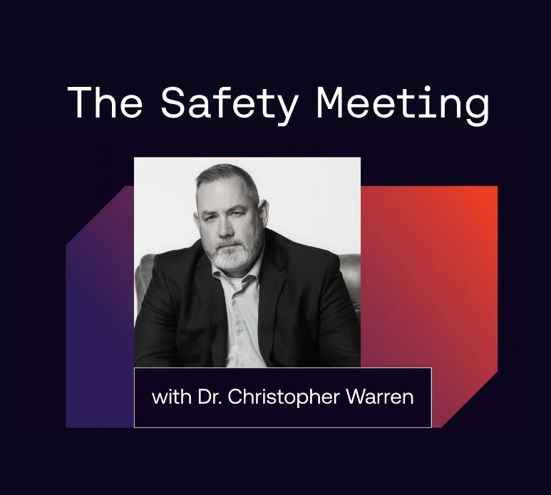 A man in a suit sits for a portrait. Text above reads “The Safety Meeting” and below reads “with Dr. Christopher Warren.” The background features dark and red geometric shapes.